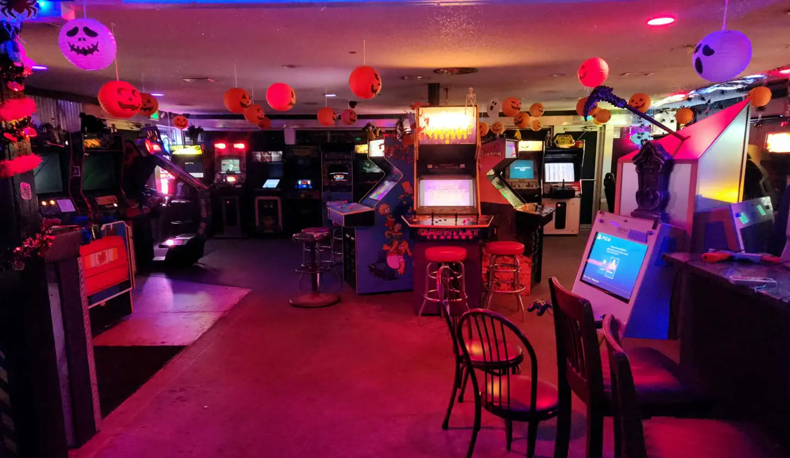 Wide view of the arcade floor with Gauntlet Legends, The Simpsons and rows of lit cabinets